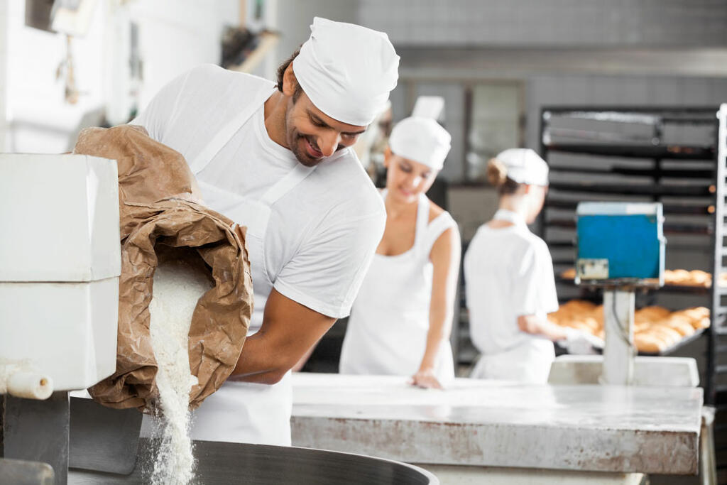 Pouring Flour in mixer for making bread at Gregory''s Foods in Eagan